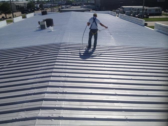 Roofer spraying a coating over a metal roof